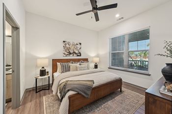 A bedroom with a large bed, a ceiling fan, and a window with blinds at The Concord Luxury Apartments, Sarasota, FL, 34240